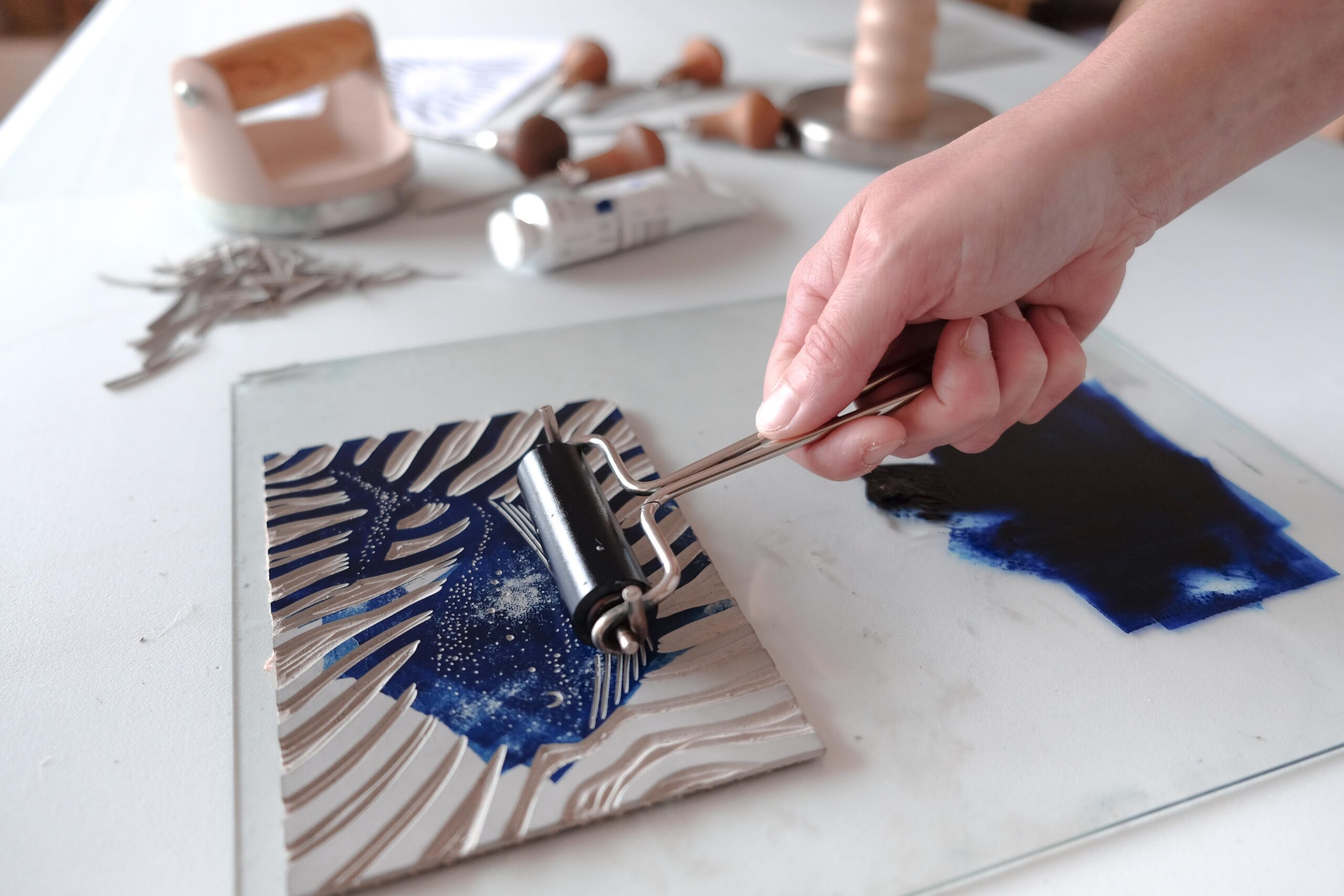 Application uniforme de l'encre à base d'eau sur le relief d'une matrice gravée avec un rouleau brayer.